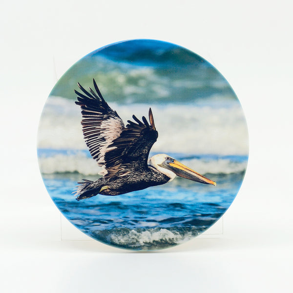 A flying pelican over the ocean photograph on a round rubber home coaster