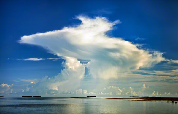 A photo of the ocean with a beautiful blue sky and white puffy clouds